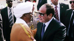 Sudanese President Omar al Bashir (L) welcomes Egyptian President Abdel Fattah al-Sisi upon his arrival at Khartoum airport for an official visit on June 27