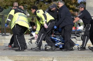 Paramedics and police pull a victim away from the Canadian War Memorial in Ottawa, Ontario, on Wednesday, Oct. 22, 2014. A soldier standing guard at the National War Memorial was shot by an unknown gunman and people reported hearing gunfire inside the halls of Parliament. Prime Minister Stephen Harper was rushed away from Parliament Hill to an undisclosed location, according to officials. (AP Photo/The Canadian Press, Adrian Wyld)