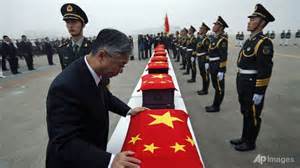 Chinese Ambassador to South Korea Qiu Guohong covers caskets containing the remains of Chinese soldiers killed during the 1950-1953 Korean War at a handing over ceremony in Incheon, South Korea
