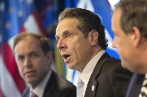 New York Governor Andrew Cuomo, center, speaks at a news conference, Friday, Oct. 24, 2014 in New York. At left is Dr. Howard Zucker, acting commissioner of the New York State Department of Health, and New Jersey Governor Chris Christie is at right. The governors announced a mandatory quarantine for people returning to the United States through airports in New York and New Jersey who are deemed "high risk." In the first application of the new set of standards, the states are quarantining a female healthcare worker returning from Africa who took care of Ebola patients. (AP Photo/Mark Lennihan)