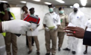 FILE - In this Monday, Aug. 4, 2014, file photo, a Nigerian health official uses a thermometer on a worker at the arrivals hall of Murtala Muhammed International Airport in Lagos, Nigeria. (AP Photo/Sunday Alamba, File)