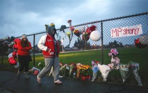 A memorial grows Saturday Oct. 25, 2014 at the entrance to Marysville Pilchuck High School the day after a shooting in the school cafeteria left two dead and four wounded. The shooter was among the dead. A first year teacher was being hailed as a hero for intervening in the shooting, possibly stopping the gunman.  (AP Photo/seattlepi.com, Joshua Trujillo)