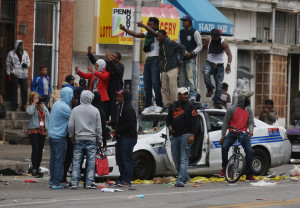 Demonstrators climb on a destroyed Baltimore police car during violent protests following the funeral of Freddie Gray April 27, 2015 in Baltimore, Maryland.