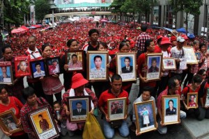 Families of those who were killed in the 2010 red-shirt riots hold photos of their loved ones. More than 10,000 supporters of the movement converged at the Ratchaprasong intersection yesterday to commemorate the third anniversary of crackdown