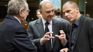 Greek Finance Minister Yanis Varoufakis, right, speaks with European Commissioner for the Economy Pierre Moscovici, center, and Italian Finance Minister Pier Carlo Padoan, left, during a meeting of EU finance ministers at the EU Council building in Brussels on Tuesday, March 12, 2015. 