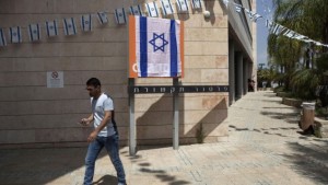 An Israeli man walks past the Orange company logo covered with an Israeli flag at Partner Communications' offices in Rosh Haayin, Israel, on June 4