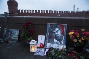 Flowers, votive candles and portraits of slain Russian opposition leader Boris Nemtsov are placed at the place where he was gunned down one year ago, with the Kremlin Wall in the background, in Moscow, Russia, early Saturday, Feb. 27, 2016. The sign in center reads "1 year." 