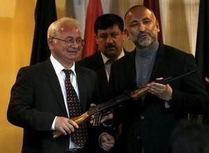 Russia's ambassador, to Afghanistan Alexander Mantytskiy (L) hands over an AK-47 to Afghan national security adviser Hanif Atmar (R) after a conference at the International Kabul Airport, Afghanistan February 24, 2016.  