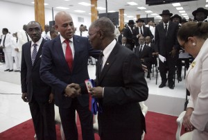 Haiti's outgoing President Michel Martelly (2L) shakes hands with the Senate President Jocelerme Privert (C) in presence of the Prime Minister Evans Paul during a ceremony marking the end of Martelly's presidential term, in the Haitian Parliament in Port-au-Prince, Haiti, February 7, 2016.