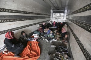 Syrians gather inside a truck to protect themselves from the cold weather at the Bab al-Salam border gate with Turkey, in Syria, Saturday, Feb. 6, 2016. 
