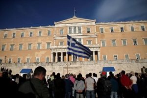 A protester waves a Greek flag during a demonstration outside the parliament building in central Athens, Greece where lawmakers were discussing controversial tax and pension reforms May 8, 2016.