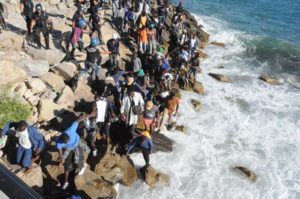 Migrants walk on the rocks as they try to get to the sea past a Police cordon in Ventimiglia, an Italian town on the border with France, Friday, Aug. 5, 2016. Italian and French Police reportedly fired tear gas trying to prevent the migrants from reaching France.