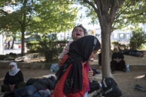 A woman carries her crying baby in a park, at the northern Greek city of Thessaloniki, on Saturday, July 9, 2016. 