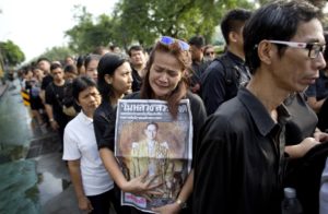 A Thai woman weeps as she holds on to a portrait of Thai King Bhumibol Adulyadej in a line to offer condolences for the king at Grand Palace in Bangkok, Thailand, Friday, Oct. 14, 2016. Grieving Thais went to work dressed mostly in black Friday morning, just hours after the palace announced the death of their beloved King Bhumibol, the politically fractious country's unifying figure and the world's longest-reigning monarch.