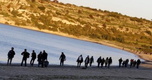 Refugees walk along a beach before trying to travel to the Greek island of Chios from the western Turkish coastal town of Cesme, in Izmir province, Turkey, March 5, 2016. 
